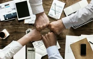 Quatre poings réunis au-dessus d'un bureau montrent la pertinence d'un travail d'équipe