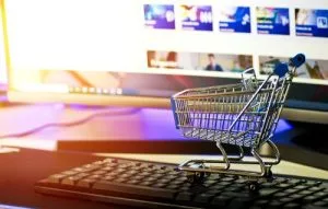 caddie sur clavier d'ordinateur, des vignettes à l'écran de l'ordinateur. Montre le rôle décideur de la publicité dans l'acte d'achat