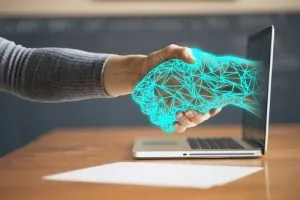 Poignée de mains entre un humain et une personne virtuelle, sortant de l'écran d'un ordinateur. Coopération entre le DPO d'une structure et le DPO expert de Conformity Data